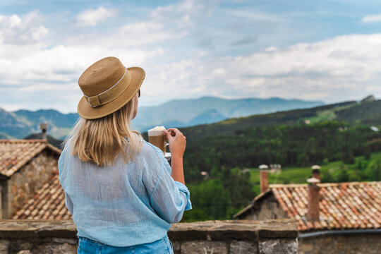 Woman enjoying cappuccino with panoramic countryside and mountain view