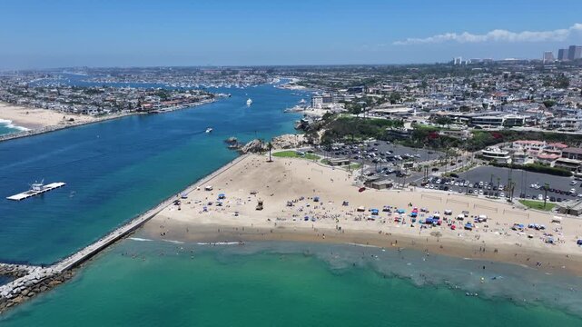 flying along Corona del Mar State Beach, located in Corona del Mar, a seaside neighborhood in the city of Newport Beach, California with many people sunbathing at the beach and swimming in the Ocean