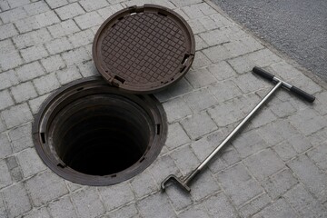 Naklejka premium Manhole Cover Lifting Tool Beside Open Utility Access Point for Professional Maintenance Operations Worldwide Today
