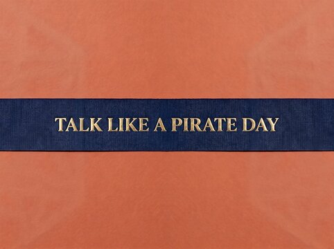 Talk Like a Pirate Day text on ribbon with orange background
