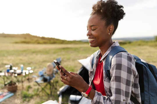 Woman Checks Smartphone at Campsite During Outdoor Adventure