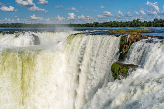 Scenic view of a powerful waterfall in the Brazilian rainforest with lush green vegetation and blue sky
