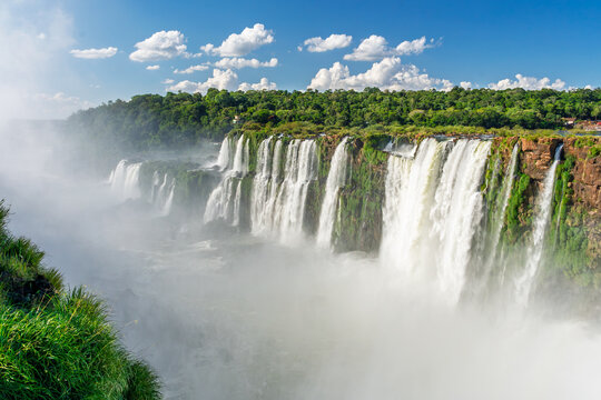 Scenic view of a massive waterfall cascading over cliffs into a misty river in the lush tropical rainforest of Brazil