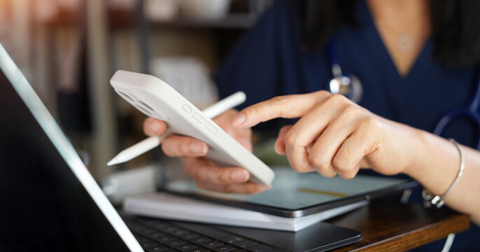 Healthcare Professional Tapping Smartphone While Using Tablet And Laptop For Telemedicine, Medical Records And Patient Care. Digital Health Technology Supporting Clinical Communication And Workflow.