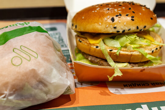 Delicious beef burger with cheese and fresh lettuce in a cardboard box next to wrapped sandwich