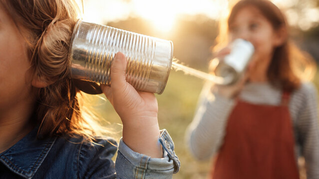Children playing tin can telephone outdoors