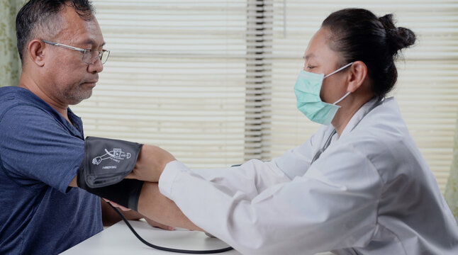 Female doctor checking blood pressure of a senior man