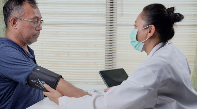 Female doctor examining a senior man blood pressure