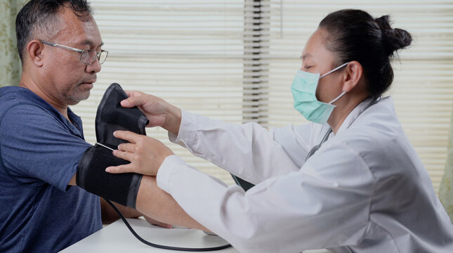 Female doctor wrapping blood pressure cuff on a patient arm