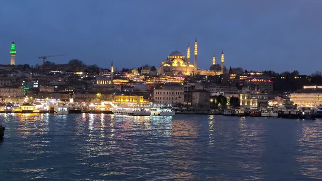 Wide angle dusk shot of the illuminated S&uuml;leymaniye Mosque and historic Istanbul skyline reflected in the glowing waters of the Bosphorus Strait, Turkey.