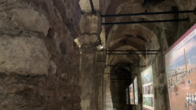 Slow tracking shot through the ancient stone arches and vaulted ceiling of the historic Basilica Cistern, displaying ornate columns and heritage exhibits in Istanbul, Turkey.