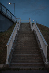 Fototapeta premium Long concrete staircase with white railings against twilight sky