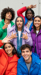 Fototapeta premium Group portrait of diverse young adults in colorful puffer jackets, conveying youthful energy and camaraderie, showcasing casual fashion and friendship.