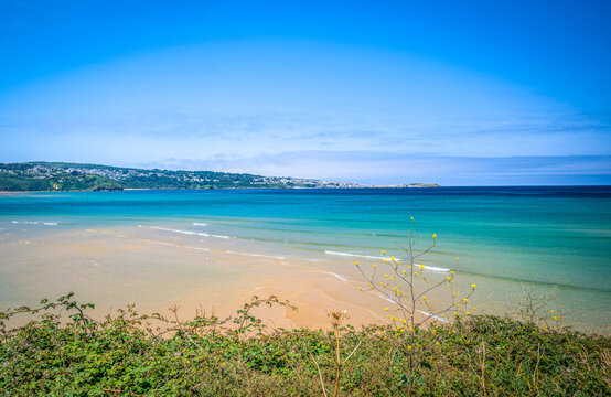A beach with a cliff in the foreground and a headland on the horizon.