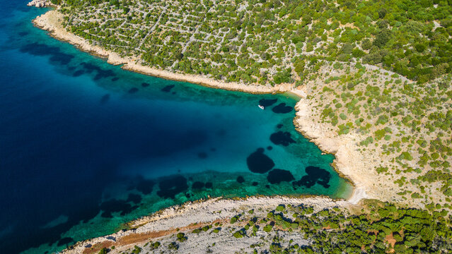 Aerial view of a stunning Croatian cove with turquoise waters, lush green shores, and a solitary boat. Perfect for summer escapes. Beach Grabrovica