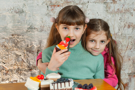 Two girls enjoying cupcakes in a cozy room with a rustic background during the afternoon