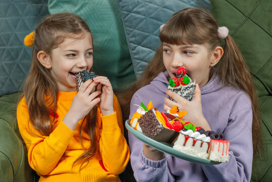 Two girls enjoy sweet treats while sitting on a couch in a cozy living room
