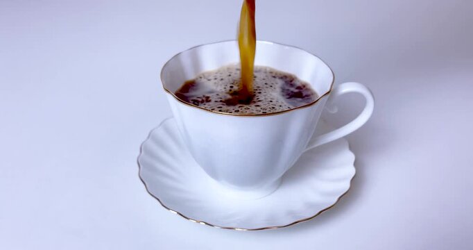 Freshly brewed hot black coffee being poured into elegant white porcelain cup for breakfast.