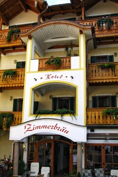 Traditional alpine Hotel Zimmerbrau building facade with wooden balconies green shutters and white arched entrance gate in historical village of St Gilgen. Salzburg, Austria - August 14, 2009