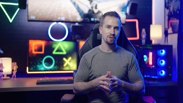 Gamer influencer enthusiastic explaining to camera in gaming cyberspace room