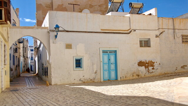 Arch over an alley, beside a building with a blue door, in the medina, in Kairouan, Tunisia