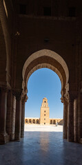 Fototapeta premium Minaret of the Great Mosque of Kairouan, framed by an arch in the patio around the courtyard, in the medina, in Kairouan, Tunisia