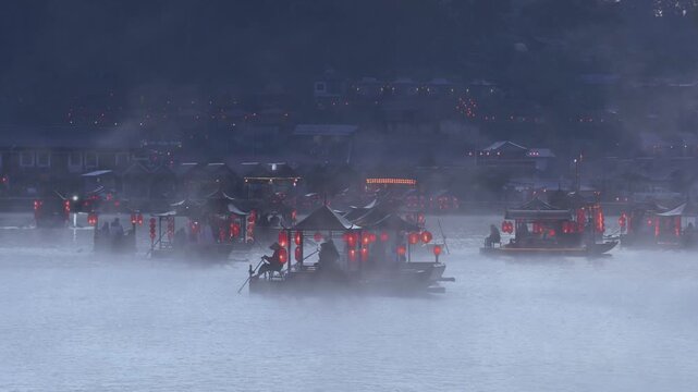 Rak Thai Village, Mae Hong Son, Thailand - November 25, 2025: Traditional Chinese-style boats sail on a misty lake during a beautiful winter at Ban Rak Thai village. Famous travel destination.