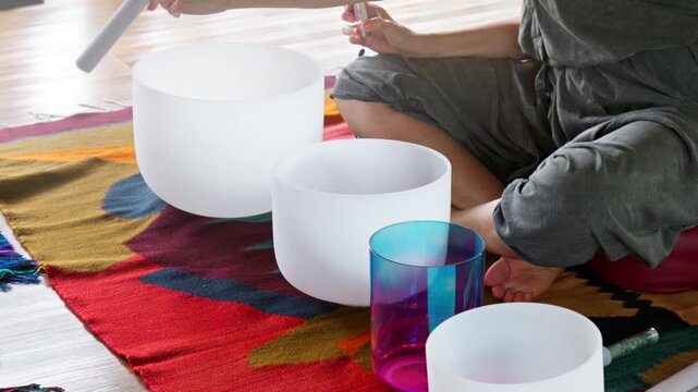 Hands playing on white quartz crystal singing bowls in the gazebo. Healing medicine and meditation
