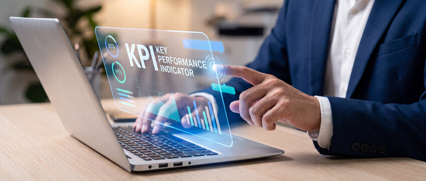 KPI key performance indicator business dashboard projected as a glowing blue holographic interface from a laptop used by a businessman in a suit for corporate data analysis