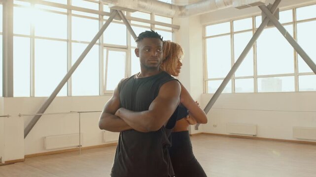African Fitness Couple Back-to-Back in Bright Studio Gym Portrait Showing Confidence and Strength, and woman and man trainers stand in the fitness room, in sunlight fitness and healthy lifestyle 4K