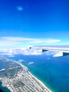 Aerial view of Miami coastline and islands from airplane window during daytime flight