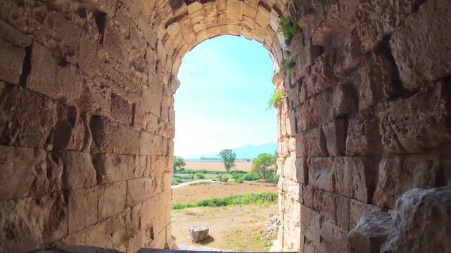 Interior view through a dark stone-vaulted corridor and archway inside the ancient Roman theater at Miletus, Turkey.