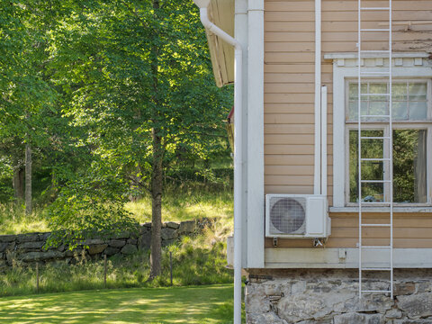 Air source heat pump outdoor unit installed on the exterior wall of a residential house.