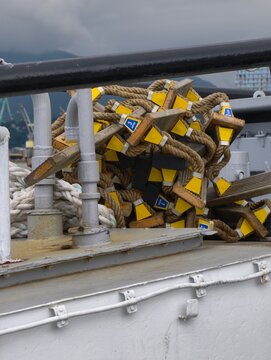 Coiled rope ladders with wooden rungs and yellow depth markers stacked on the deck of a fishing vessel. Marine equipment used for commercial fishing and ship operations.