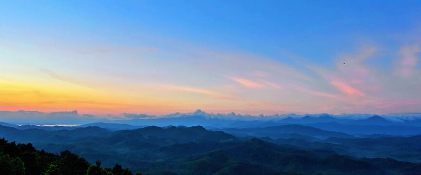 A sweeping panoramic view of densely forested mountains stretching to the horizon under a clear blue sky with soft sunlight. Beautiful natural scenery, ideal for nature, conservation, ecotourism. 4K