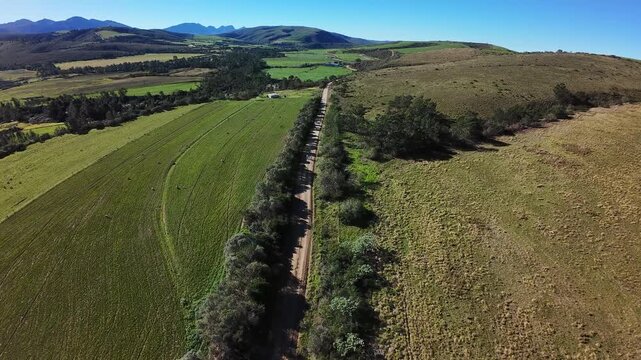 Aerial shot of two mountain bikers cycling down a gravel road through lush farmlands