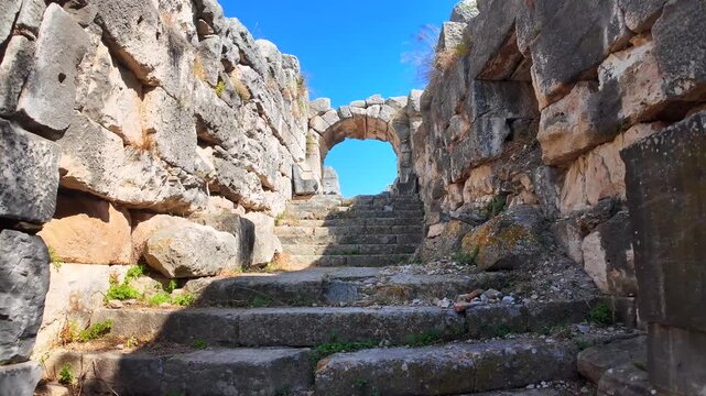 View of a narrow open-air stone corridor between massive ruined blocks at the ancient Miletus theater site in Turkey.