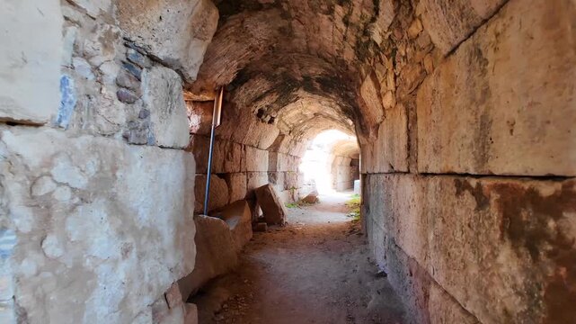 Interior view looking through a dark stone vaulted corridor and archway inside the ancient Roman theater at Miletus, Turkey.