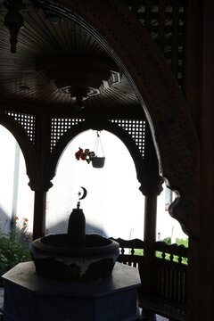 Traditional wooden sebilj fountain inside an ornate pavilion with Islamic crescent moon and star symbol.
