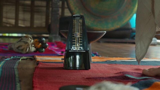 An old mechanical metronome stands on the floor counting down the rhythm.