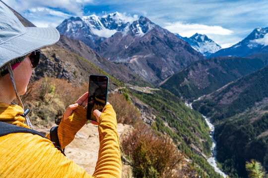 Mujer senderista tomando una fotograf&iacute;a con su celular de las magnificas vistas de los himalayas, en su camino al campamento base del everest.