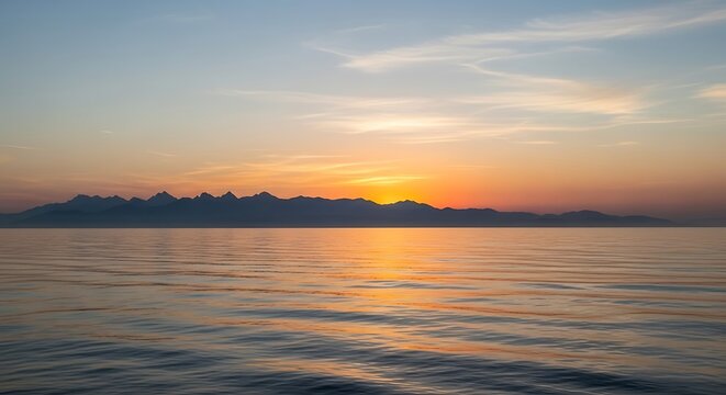 Golden sunset over calm lake with distant mountains.