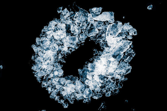 Ice cubes crush on black background. Chill backdrop. Frame border, in a round shape, made of ice. Space for copy.