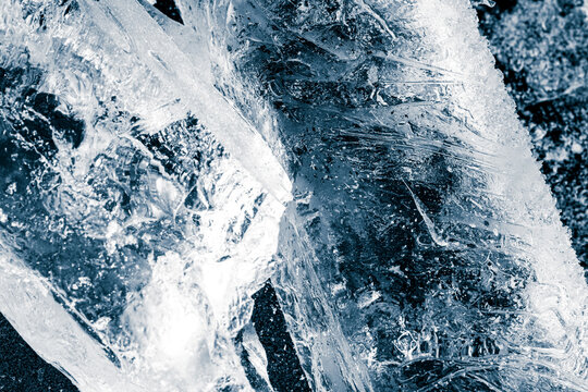 Textured, transparent rectangular ice blocks on a black ice surface. Cold freshness concept background.