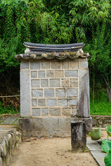 Obraz premium Traditional Stone Wall with Tiled Roof and Lush Green Background