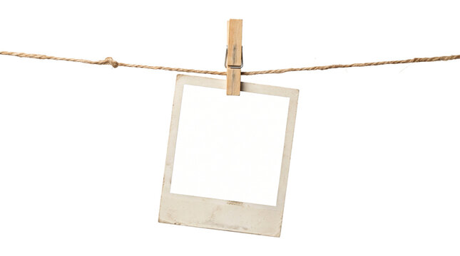 Vintage polaroid paper photo frame hanging on rustic twine rope with wooden clothespin isolated white.