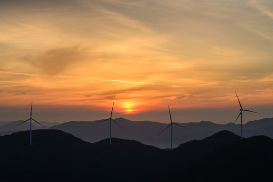 Golden Sunrise Over Mountain Wind Farm, Silhouetted Turbines Powering the Shift Toward Clean, Renewable Energy