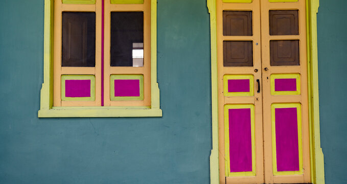 Fachada colonial con puerta y ventana de colores vibrantes en arquitectura tradicional latinoamericana