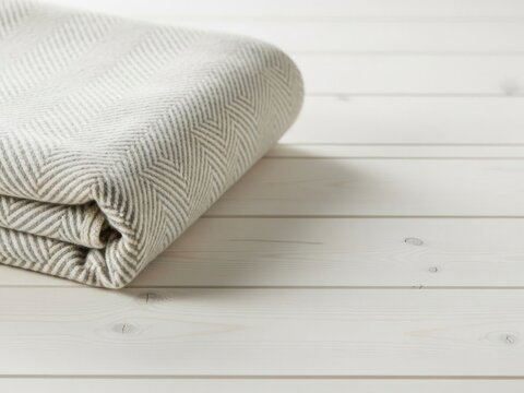 Folded herringbone blanket on white wood background for cozy home decor