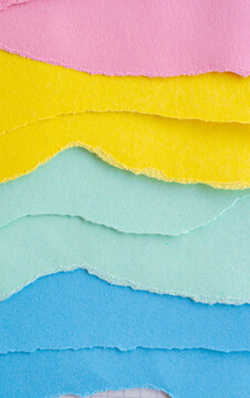 Fondo abstracto de capas de papel rasgado en tonos pastel rosa, amarillo y azul con textura artesanal